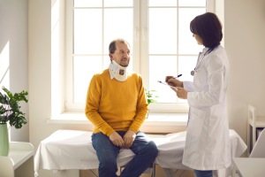 Senior man wearing neck brace listening to doctor at hospital. Traumatologist talking to senior male patient in cervical collar. Medical interview, professional help, injury treatment after accident