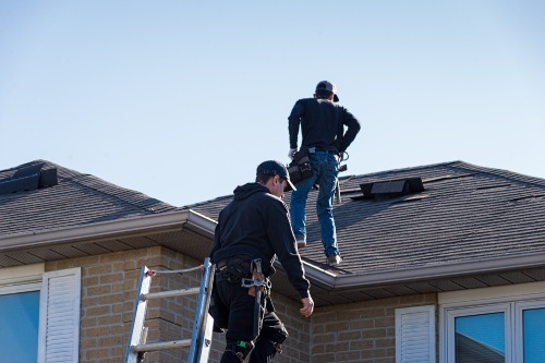 Two roofers inspecting a damaged roof