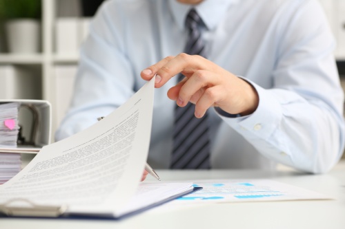 Male hands hold documents with financial statistics at office workspace closeup. White collar check money papers stock exchange market internal Revenue Service inspector earning list concept