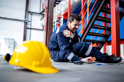 Injury at work. Factory worker fell down and injured shoulder at work.