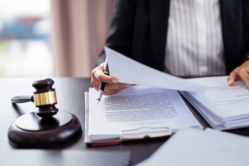 Lawyer businesswoman holding document to reading lawsuit and checking about financial business data while analysis about legislation agreement and terms data of business contract in law firm.