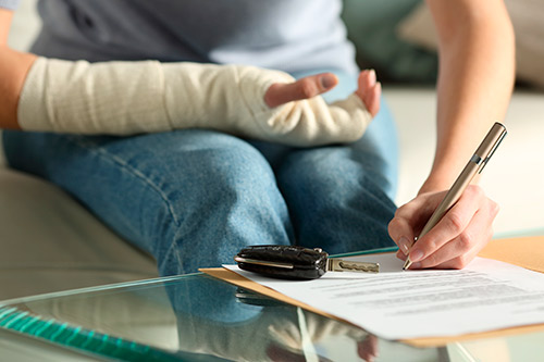 Person with arm injury signing and doing a claim form. 