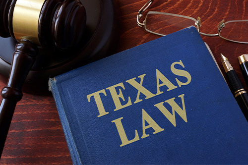 Texas law book, gavel, glasses, and pen on a desk, emphasizing legal support for storm damage claims in San Angelo.