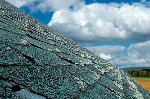 A clear blue sky with clouds above a roof, representing support for Fredericksburg hail claims in challenging situations.