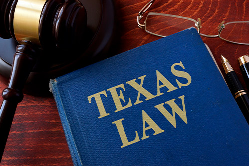 Texas law book, gavel, glasses, and pen, symbolizing legal guidance for Fredericksburg hail claims and compensation.