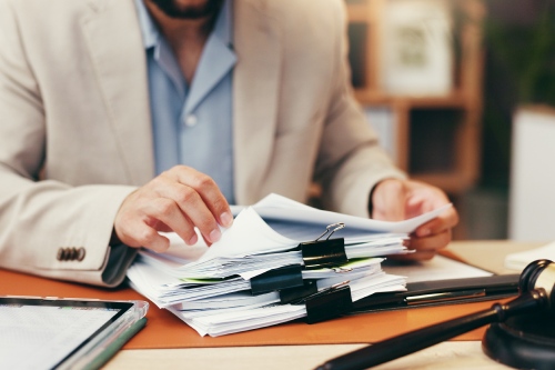 Hands, judge and stack with documents at office for legal review, administration and investigation. Person, paperwork and overwhelmed with deadline, time management and gavel for law, justice or case