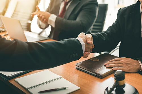 Dos hombres de negocios se estrechan la mano en una reunión, representando la asociación y la negociación en un entorno empresarial.