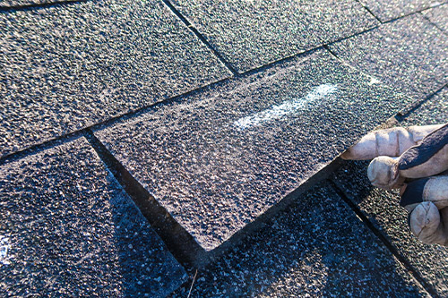 A person repairs a roof with a hammer, addressing hidden issues from hail damage after the recent storm in Boerne.