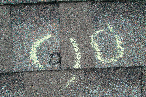 A roof featuring a smiley face, representing optimism in the face of increased insurance claim denials after Texas hailstorms.