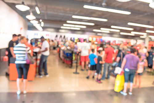 Imagen borrosa de compradores en una tienda, destacando el ambiente ajetreado durante los preparativos de las compras navideñas.
