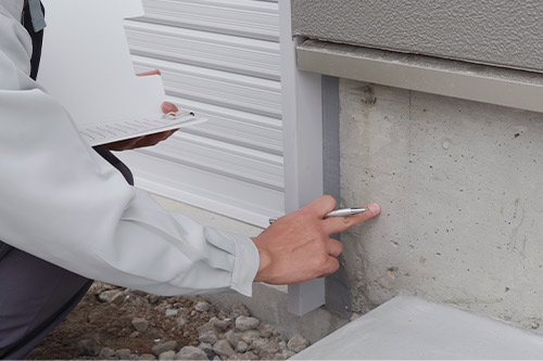 A man inspects a wall with a pen, illustrating a step from the guide on appealing winter storm damage claims.