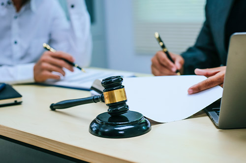  A lawyer and judge in an office setting, reviewing documents and a laptop about winter storm damage claim appeals.
