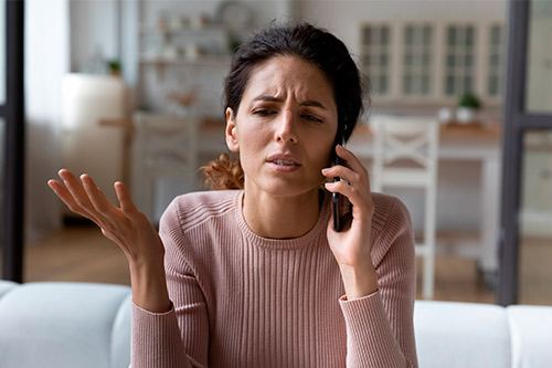 A woman on a cell phone, engaged in a conversation about custom homes and pre-built homes in Harlingen, TX.