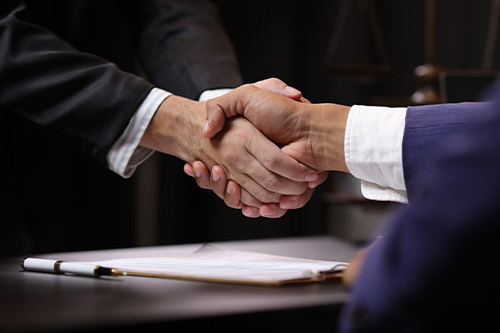 Dos empresarios se dan la mano en un escritorio, representando la colaboración en las denegaciones de reclamaciones de seguros de fin de año.