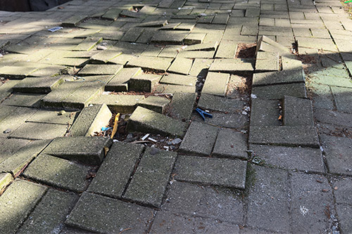 A damaged brick showing cracks, emphasizing risks associated with slip and fall accidents in the environment.