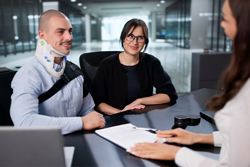 A man and woman collaborate at a desk with a laptop, exploring hidden dangers that lead to slip and fall injuries.