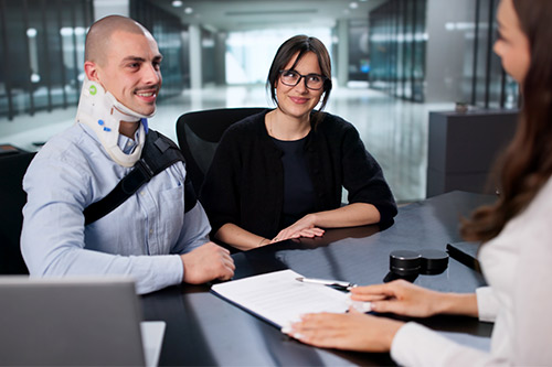 A man and woman sit at a desk with a laptop, discussing the duration of personal injury cases in Texas.