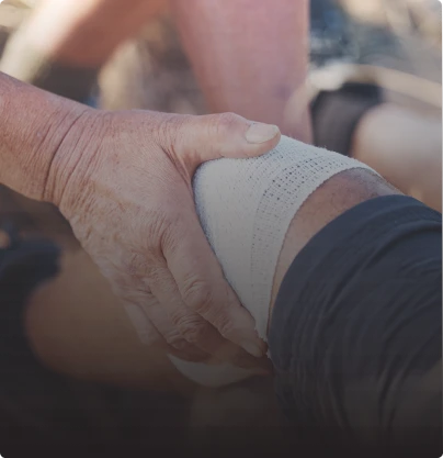 A person with a bandaged knee receives assistance from another individual after sustaining injuries 