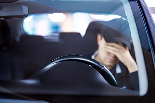 A man is seated in the driver's seat of a car, emphasizing Spring Break driving dangers on Texas highways.