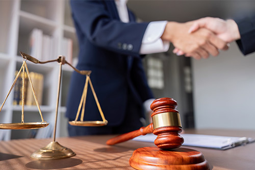 A lawyer and judge shake hands over a scale of justice, representing legal partnership in addressing Texas highway safety.