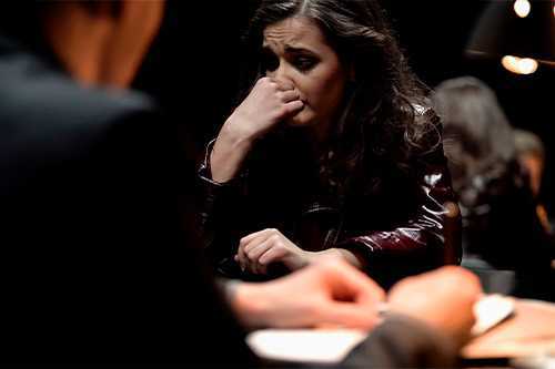 A woman seated at a table with a man in the background, discussing wrongful death damages in Texas family claims.