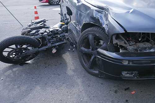 A motorcycle rests on the ground next to a car, relevant to discussions on wrongful death damages in Texas family claims.