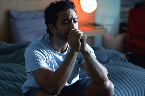 Hombre nocturno, triste y pensativo con depresión, salud mental e insomnio por estrés en dormitorio. Tarde, contemplación y persona nerviosa con ansiedad, pena o insomnio por dificultad en apartamento.