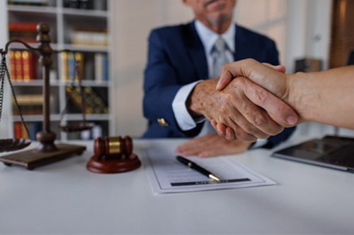 Feliz hombre de negocios de mediana edad, abogado, gerente, saludando a un cliente en la oficina. Mujer ejecutiva sonriente haciendo un trato exitoso con un socio dándose la mano en el trabajo de pie en una mesa de reuniones.