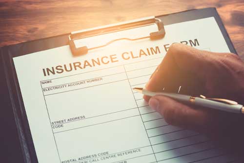Hand with pen on application form fot registering claim health insurance