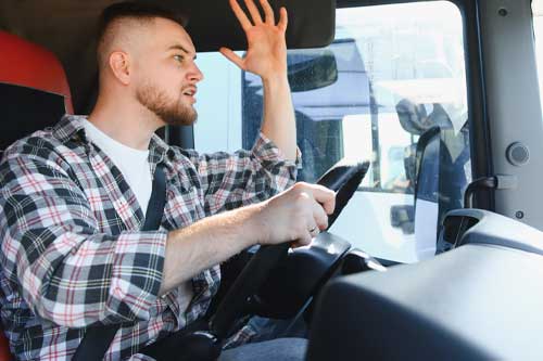 Male driver expressing anger and frustration while gesturing inside a truck cabin, feeling stressed due to traffic conditions