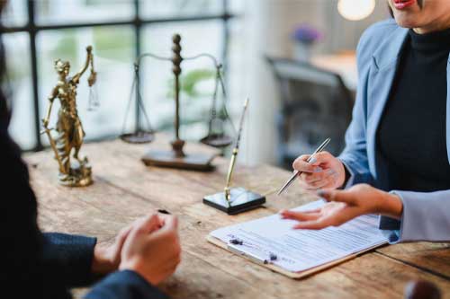 Lawyer showing contract details to client during a meeting in the office with scales of justice and gavel on the table