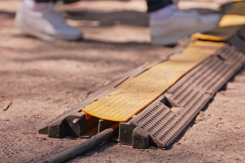 People Walking Over Heavy Duty PVC Duct Ground Cable Cover Protector used to Prevent Trip Hazard in Outdoor Settings
